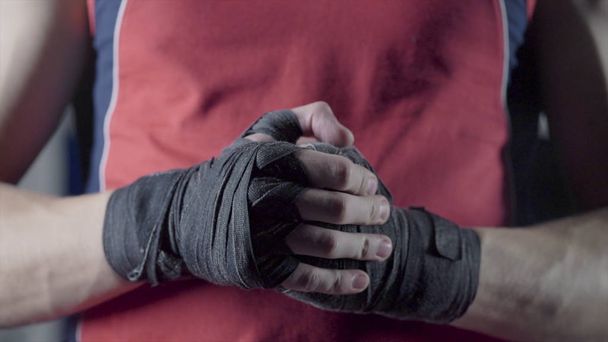 Man flexing his fists before a fight. Close-up of a young Thai boxer hands hemp ropes are wrapped before the fight or training - Photo, Image