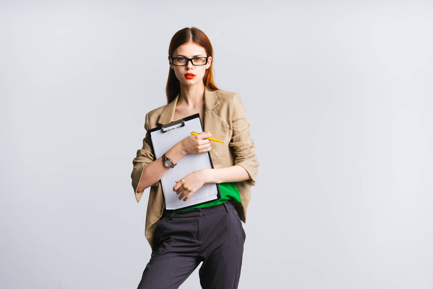 Strict confident young woman in a suit holds papers and looks frightened - Foto, imagen