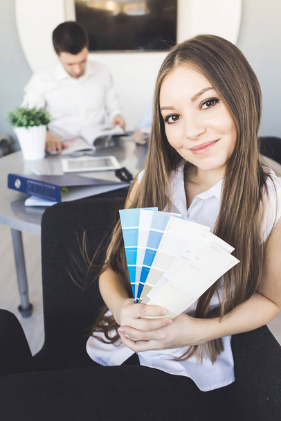 Woman designer sitting in office and choosing colors on pallet - 写真・画像