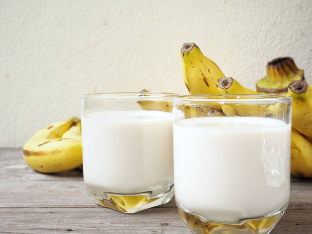 Verse melk met bananen op oude houten achtergrond - Foto, afbeelding