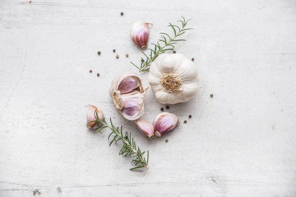Garlic. Garlic bulbs. Fresh garlic with rosemary and pepper on white concrete board - Fotó, kép