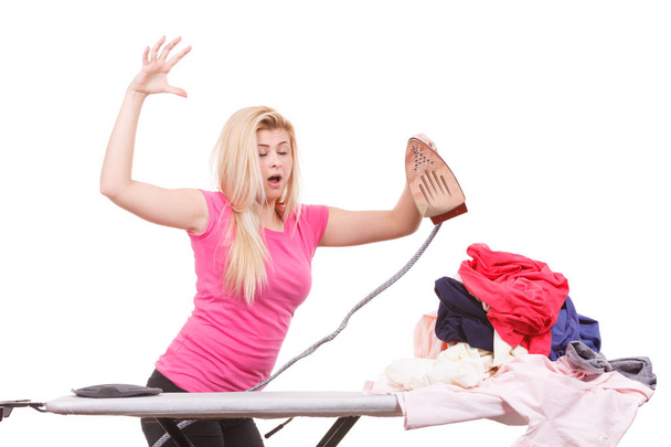 Woman holding iron about to do ironing - 写真・画像