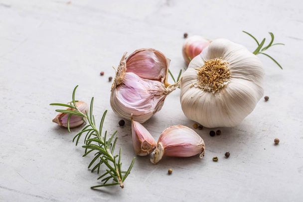 Garlic. Garlic bulbs. Fresh garlic with rosemary and pepper on white concrete board - Zdjęcie, obraz