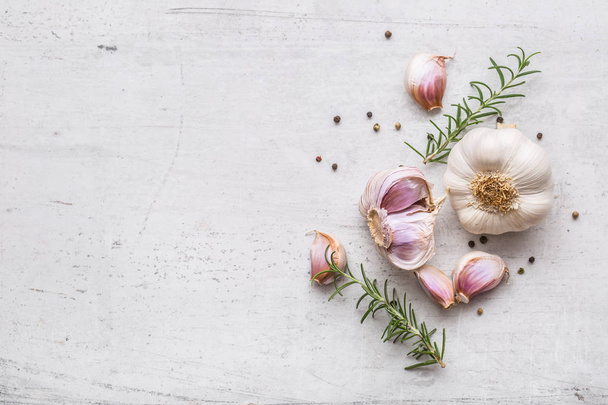Garlic. Garlic bulbs. Fresh garlic with rosemary and pepper on white concrete board - Foto, Imagem