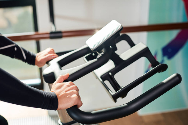Woman hands on a bar stationary bike  the gym - Foto, afbeelding