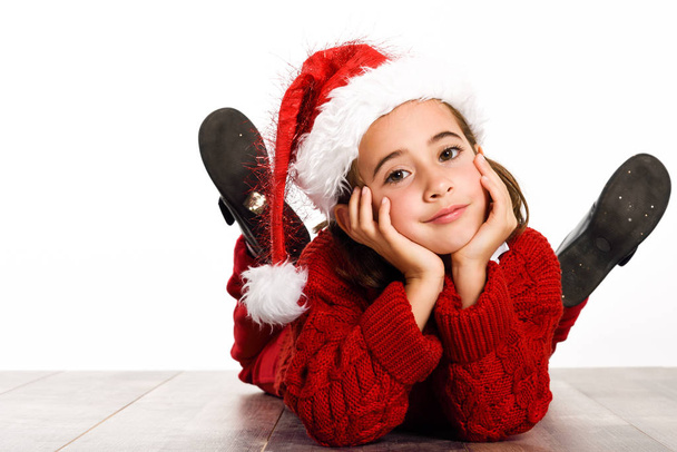 Adorável menina vestindo chapéu de Papai Noel deitado no chão de madeira
 - Foto, Imagem