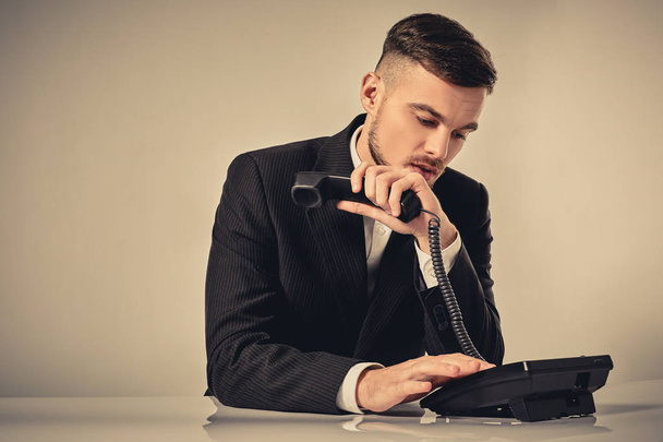 mladý muž vytočí telefonní číslo při sezení v kanceláři - Fotografie, Obrázek