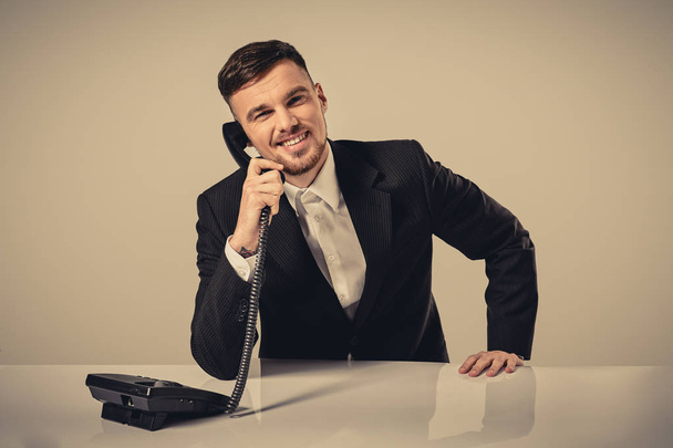 mladý muž vytočí telefonní číslo při sezení v kanceláři - Fotografie, Obrázek