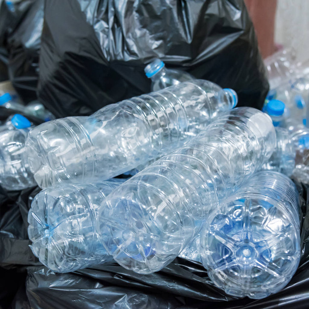 Plastikowe butelki w czarnych workach na śmieci czekające na recykling. - Zdjęcie, obraz