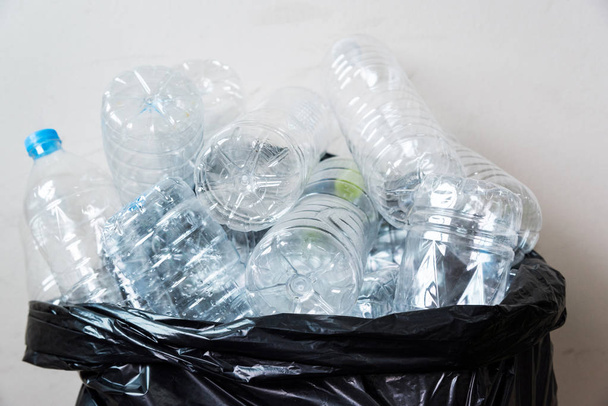 Πλαστικά μπουκάλια σε μαύρες σακούλες σκουπιδιών που περιμένουν να μεταφερθούν για ανακύκλωση. - Φωτογραφία, εικόνα