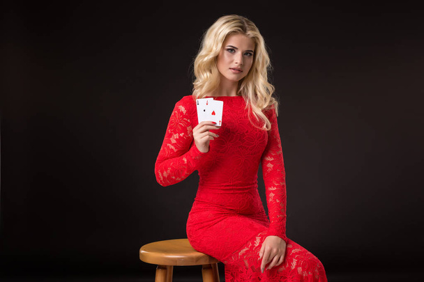 Jonge vrouw in casino met kaarten op zwarte achtergrond. Poker - Foto, afbeelding