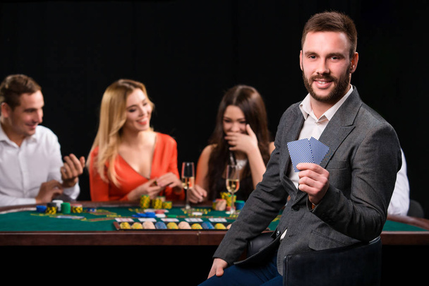 Poker players in casino with cards and chips on black background - Photo, Image