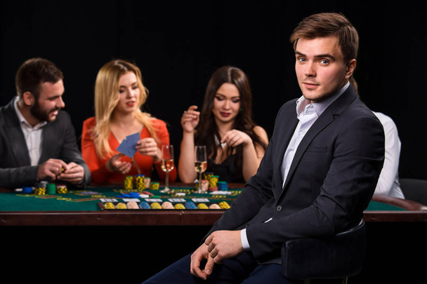 黒の背景にカードやチップを持つカジノのポーカープレーヤー - 写真・画像