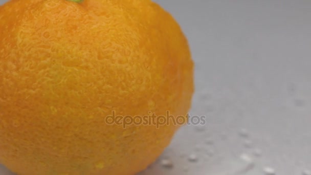 Wind blows away the drops of water from a rotating mandarin. - Felvétel, videó