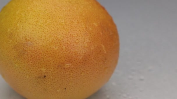 Wind blows away the drops of water from a rotating grapefruit. - Video