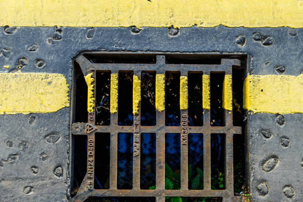 Closeup view of yellow road marking on sewer grate - Photo, Image