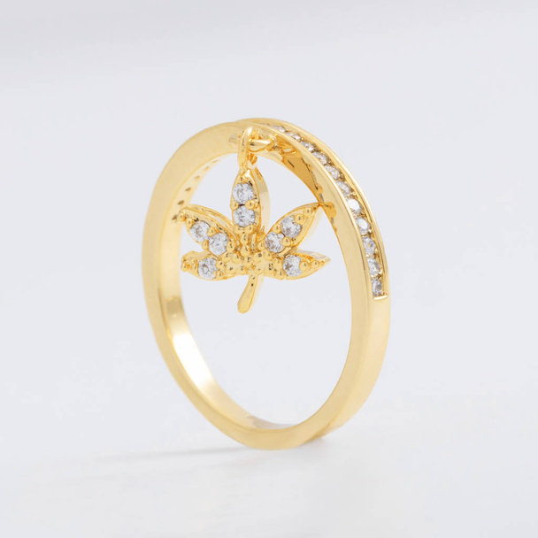 Lussuoso bellissimo anello di gioielli in oro con cristalli e strass, con una foglia decorativa su sfondo grigio
 - Foto, immagini