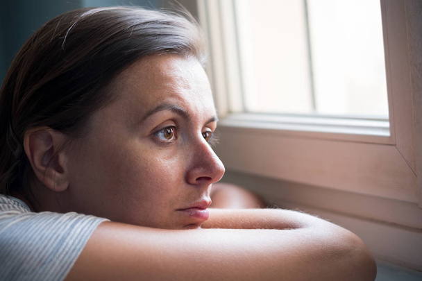 Donna triste ritratto accanto a una finestra guardando fuori
 - Foto, immagini