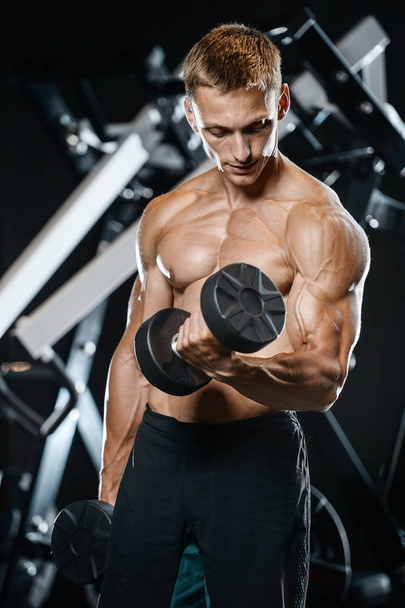 Handsome model young man training arms in gym - Photo, Image