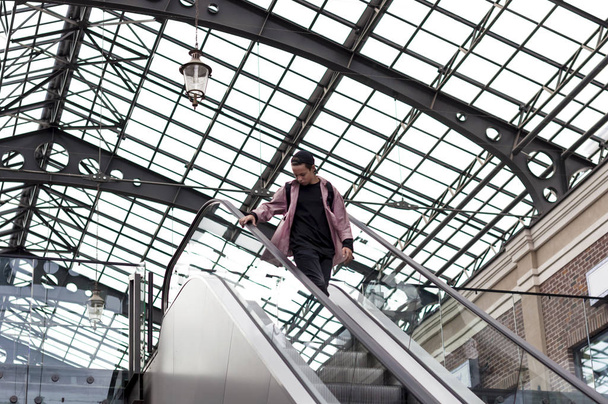 young man looking down while standing on the escalator - Foto, Bild