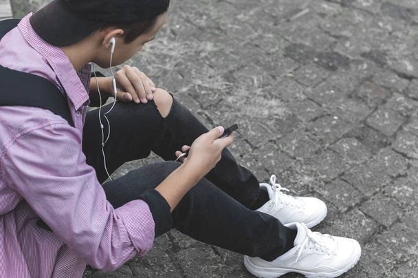 giovane con telefono seduto sul marciapiede
 - Foto, immagini