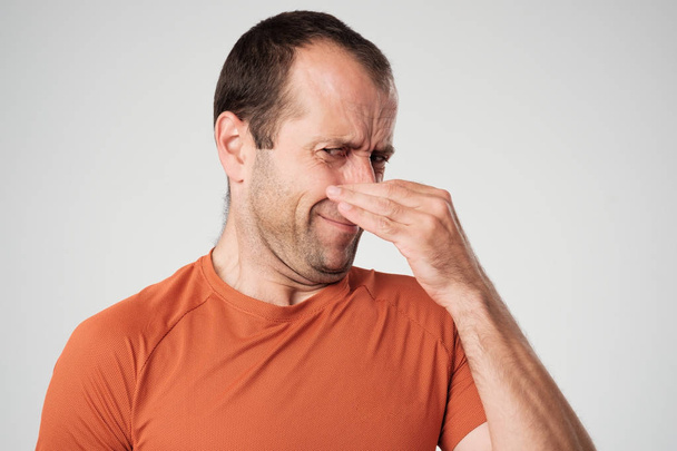Καυκάσιος ο άνθρωπος είναι τσίμπημα τη μύτη με τα δάχτυλα και κοιτάζοντας με αποστροφή λόγω άσχημη μυρωδιά που απομονώνονται σε λευκό φόντο - Φωτογραφία, εικόνα