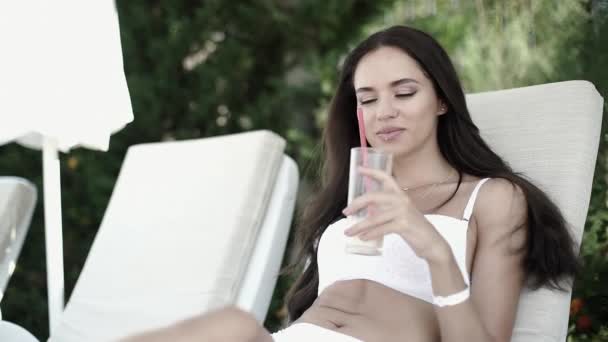 Krásná dívka opalování na relaxačním a pít koktejl - Záběry, video