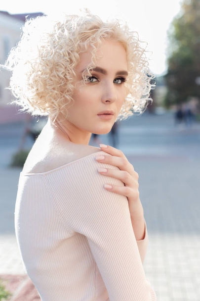 beautiful young curly blond girl outdoors in the sun at sunset on a bright day - Foto, immagini