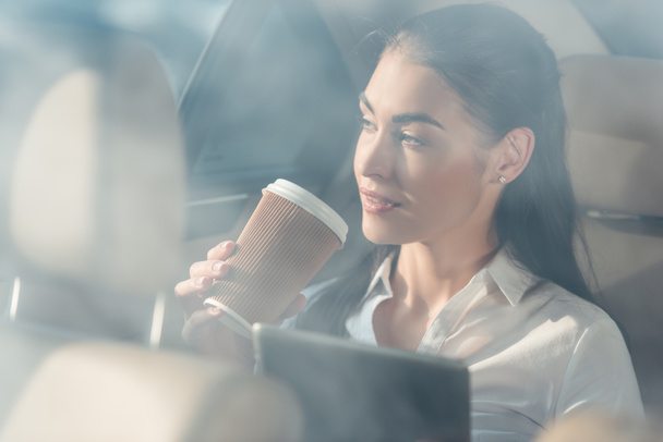 vrouw in auto met digitale Tablet PC- en koffie - Foto, afbeelding