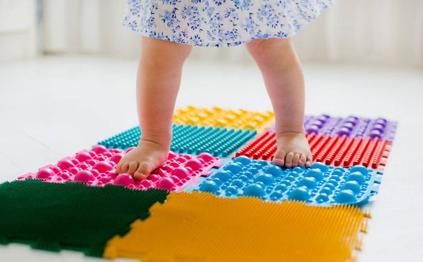 маленька дівчинка ходить на масажному килимку
 - Фото, зображення