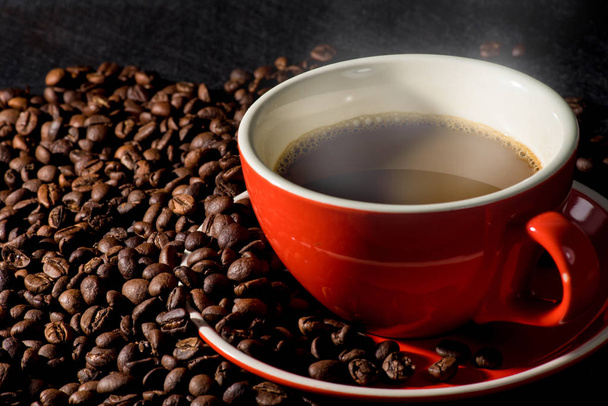 Гаряча кава в червоній чашці і кавові зерна є фоном
. - Фото, зображення