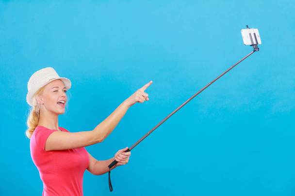 Woman taking picture of herself with phone on stick - Foto, Imagen
