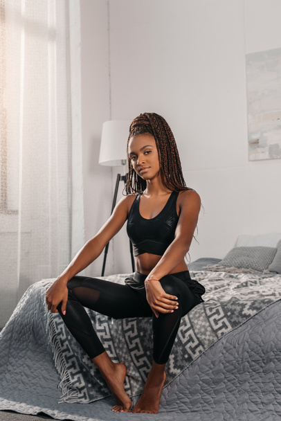 spor giyim yatağın üstüne oturan kadın - Fotoğraf, Görsel