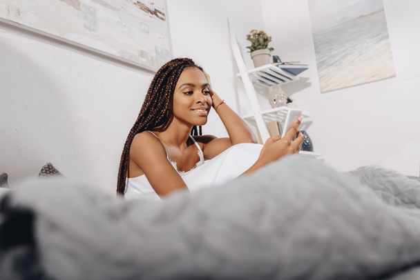Nő használ okostelefon az ágyban - Fotó, kép