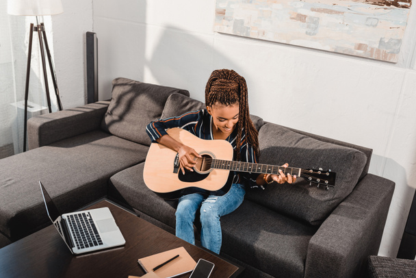  woman playing guitar on couch - Foto, imagen