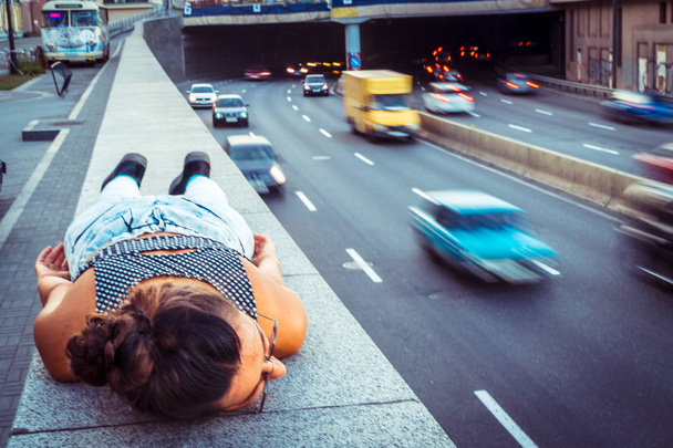 Highway. The girl is lying on the sidewalk near the motorway - Foto, afbeelding