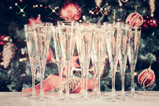 クリスマス ツリーの背景と輝くシャンパンのグラス - 写真・画像