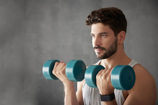 Young man using dumbbells - Foto, afbeelding