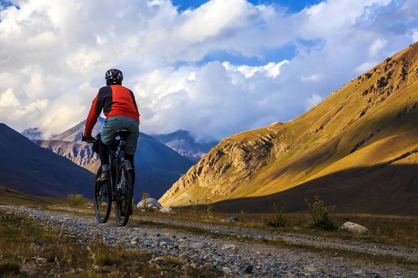Ένας άνθρωπος είναι ιππασίας ένα ποδήλατο στα βουνά. Φθινόπωρο στα βουνά. - Φωτογραφία, εικόνα
