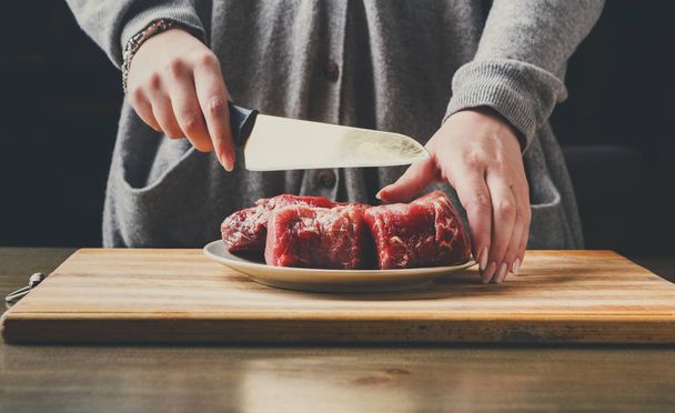 Preparazione filet mignon. Mani femminili che tagliano la carne per cucinare
 - Foto, immagini