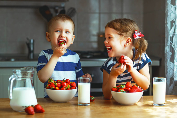 Crianças felizes irmão e irmã comendo morangos com leite
 - Foto, Imagem