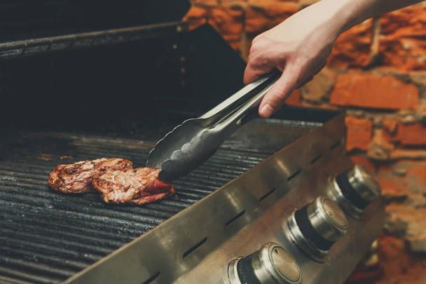 Gotowanie mięsa steki na profesjonalny grill na zewnątrz człowieka - Zdjęcie, obraz