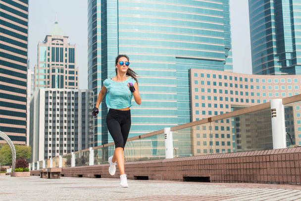 Houkutteleva urheilullinen nuori nainen käynnissä jalkakäytävällä
 - Valokuva, kuva