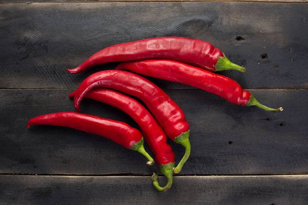 Červené chilli papričky na černé dřevěné desce - Fotografie, Obrázek