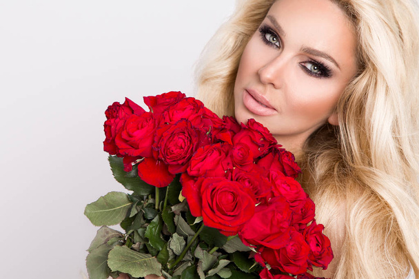 schöne sexy Blondine in eleganten Dessous auf weißem Hintergrund. Mädchen mit einem Strauß roter Rosen. - Foto, Bild