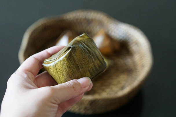 Hand holds Stuffed Dough Pyramid Dessert On bamboo pattern basket - Photo, Image