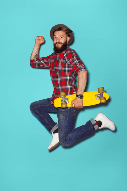 Energetic hipster jumping with longboard - Foto, Bild