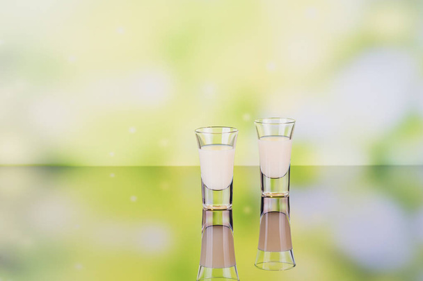 Glasses of cream liqueur on green background with reflection. - Valokuva, kuva