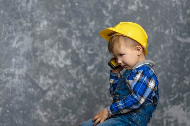 de jongen-Builder houdt de telefoon in zijn handen - Foto, afbeelding