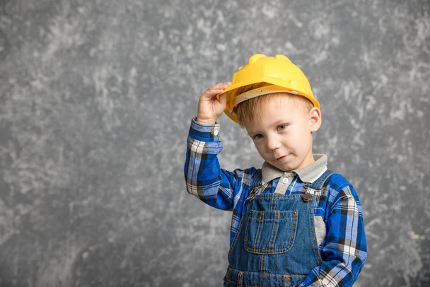 A boy holds onto a construction helmet and smiling - Φωτογραφία, εικόνα